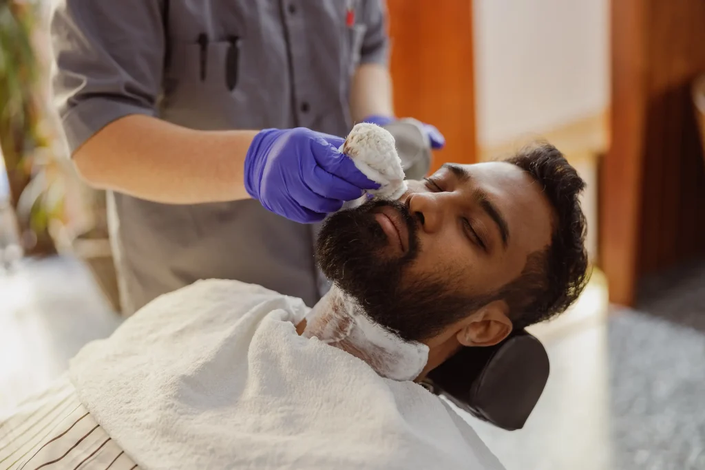 A man is enjoying a blissful and soothing beard treatment in a stylish, upscale barbershop full of ambiance
