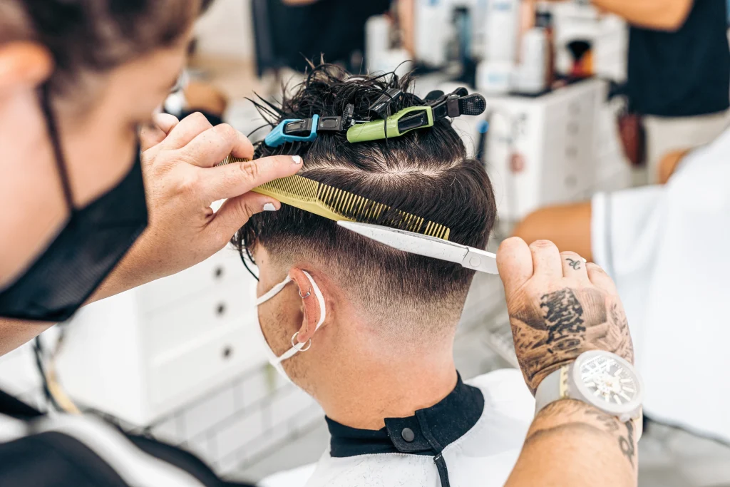 Close up view photo of a hairdresser cutting the hair of a young man