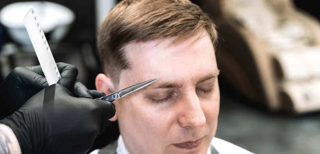 Client, customer sits in salon covered with cape
