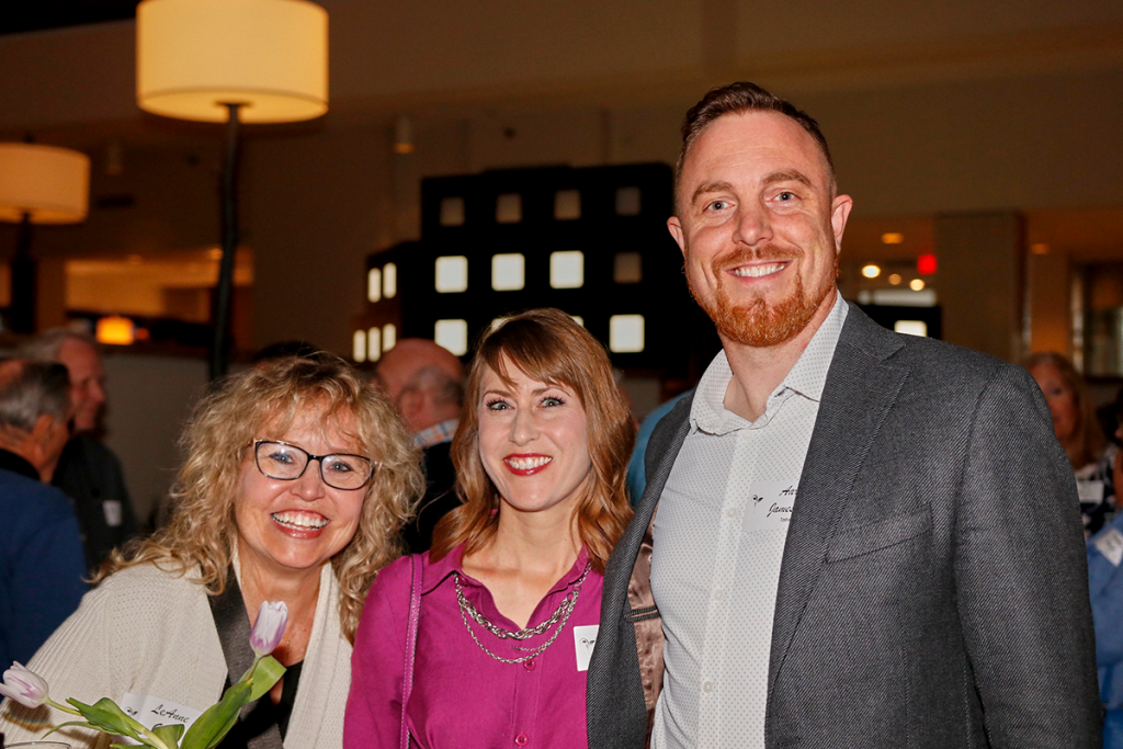 Event photography. Two women smiling and 1 man in a suit.
