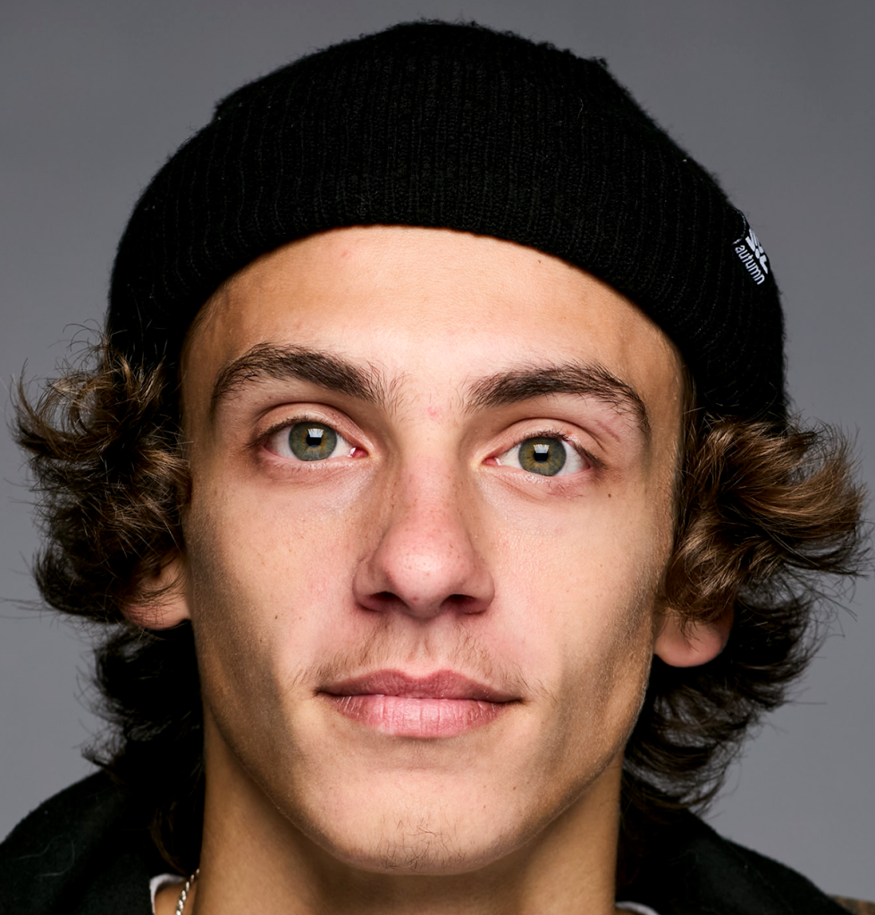 Portrait photography. Young man with wavy brown hair that has a knit cap on.