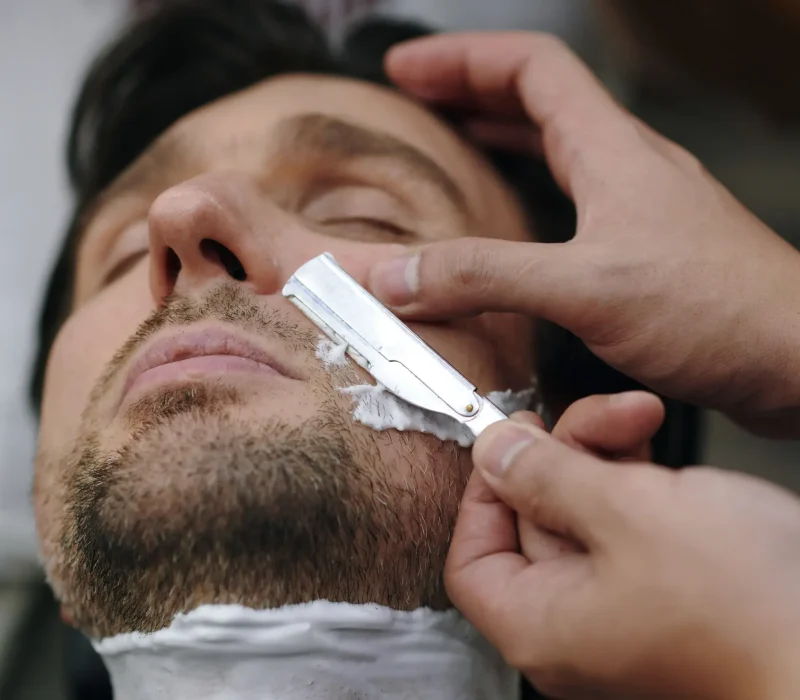 Closing image of barber using blade to clean mustache area